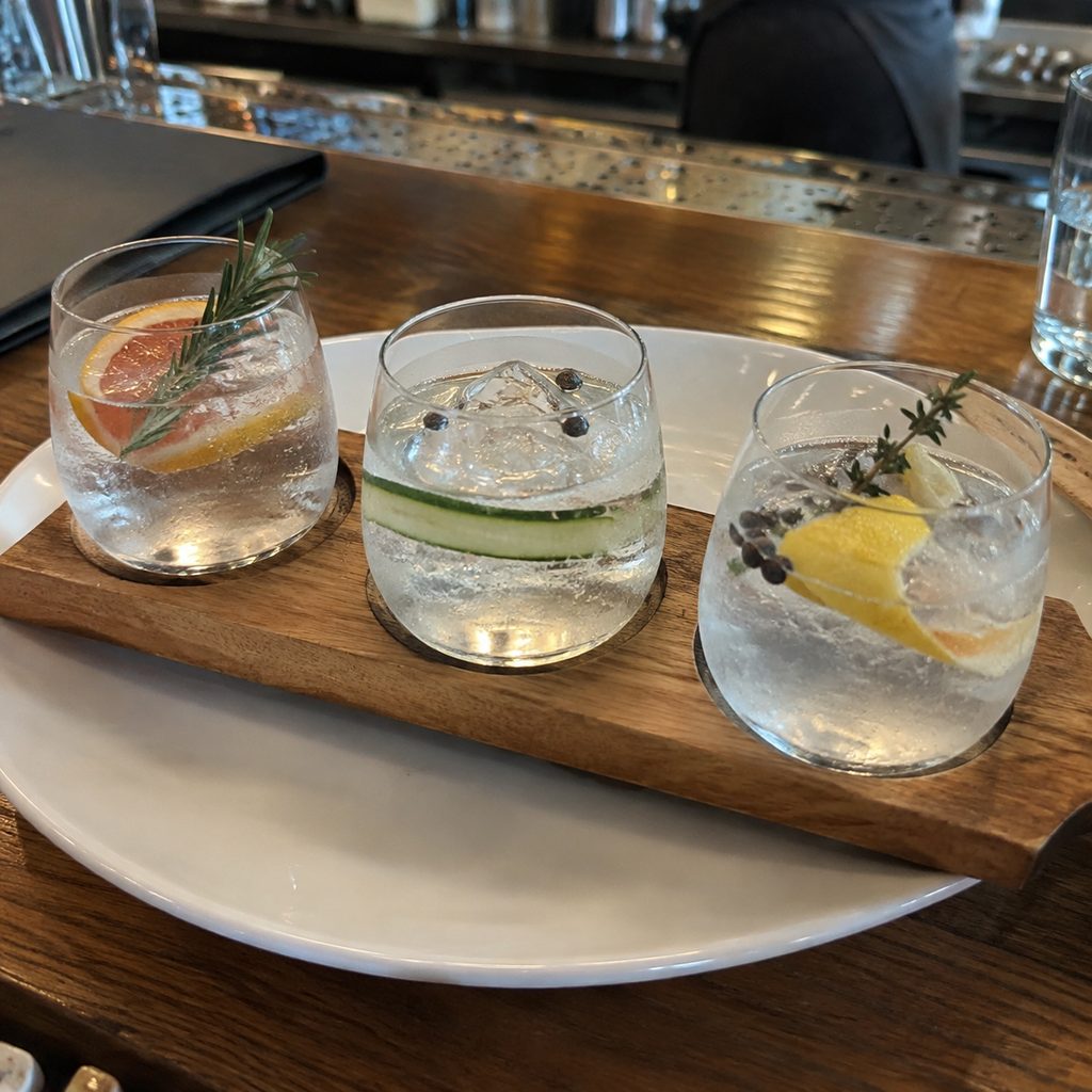 A tasting flight of three gins on a wooden board