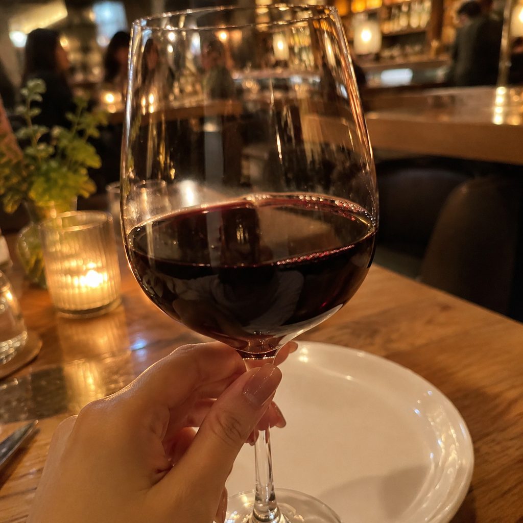 A glass of red wine held at the table