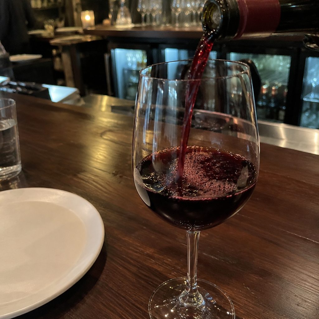 Red wine being poured into a glass at the bar